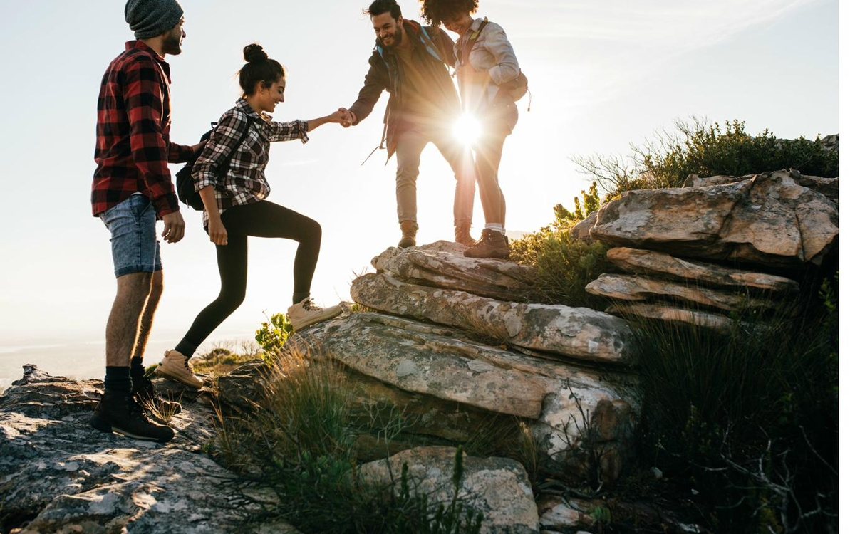 Friends helping each other up a mountain trail