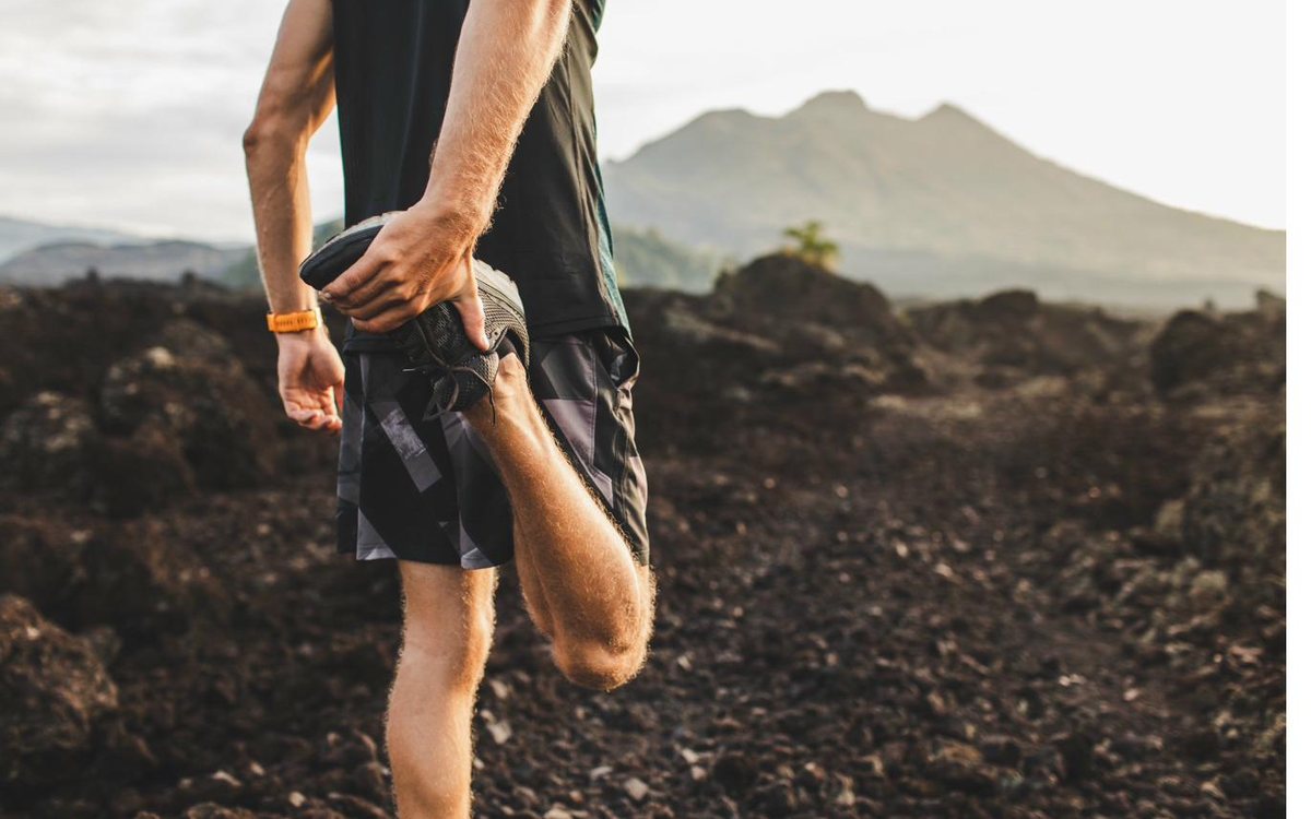 An adult stretching before a run at sunrise